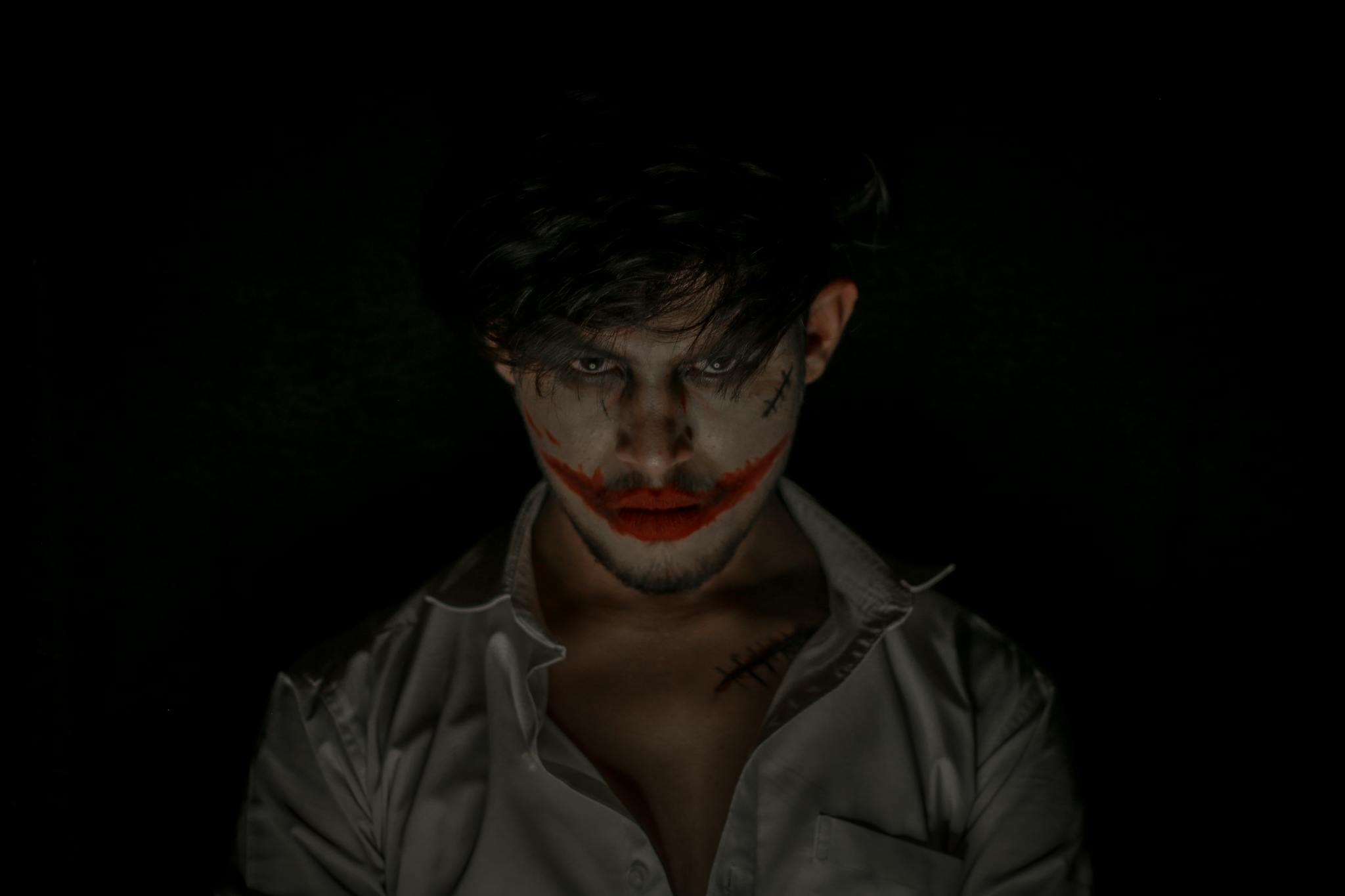 Chilling portrait of a person with eerie makeup in a dark studio setting, perfect for Halloween themes.